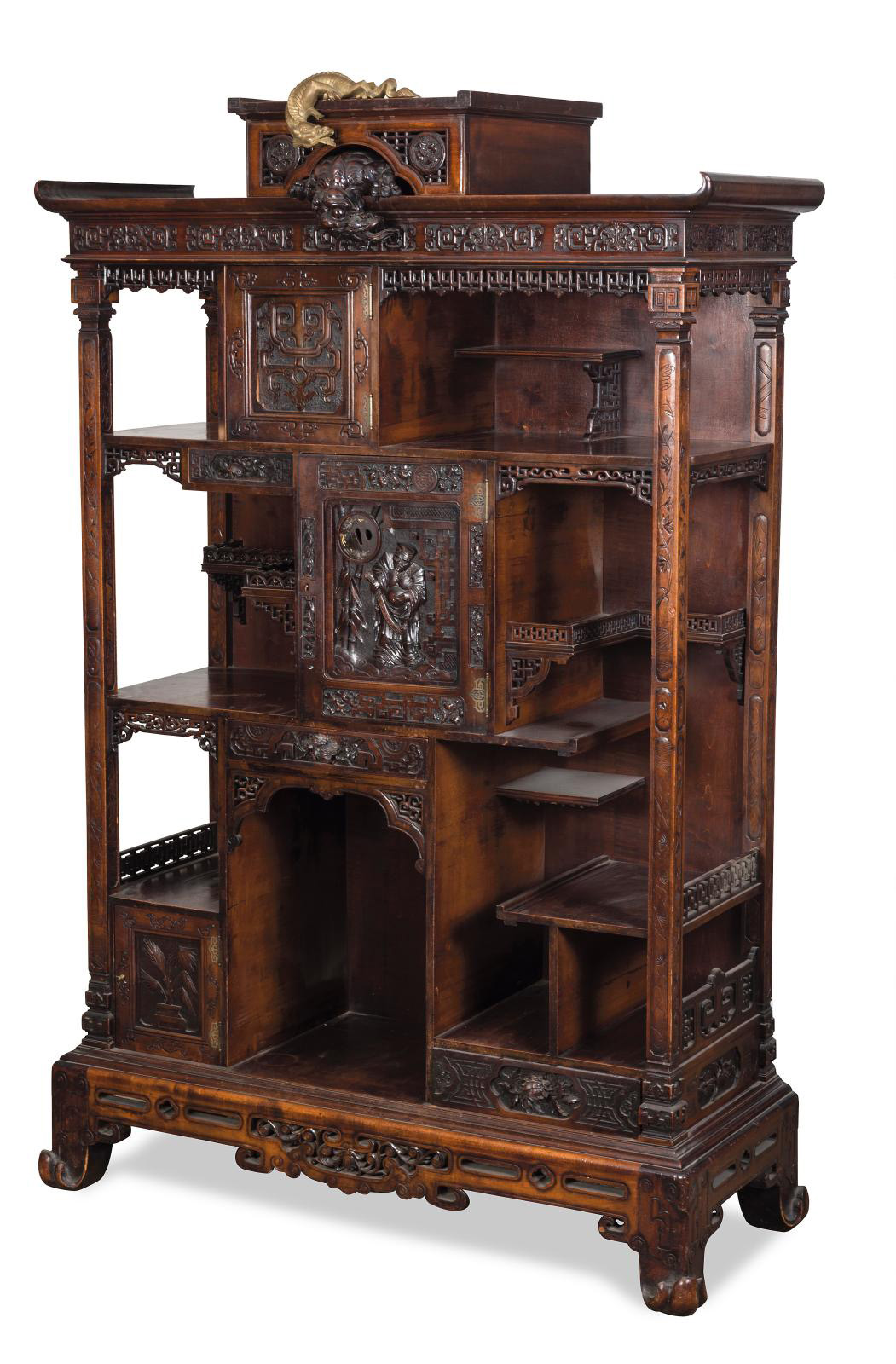 Carved, molded and patinated showcase cabinet in wood with two doors, one containing an openwork tsuba, and three drawers, Far-Eastern decoration of warriors, flowers, plants and openwork foliage, sides with unstructured shelves, a lively style base, pagoda cornice surmounted by two flying dragons, signed, 175 x 113 x 46 cm (68.9 x 44.5 x 18 in). Estimate: €1,000/1,500